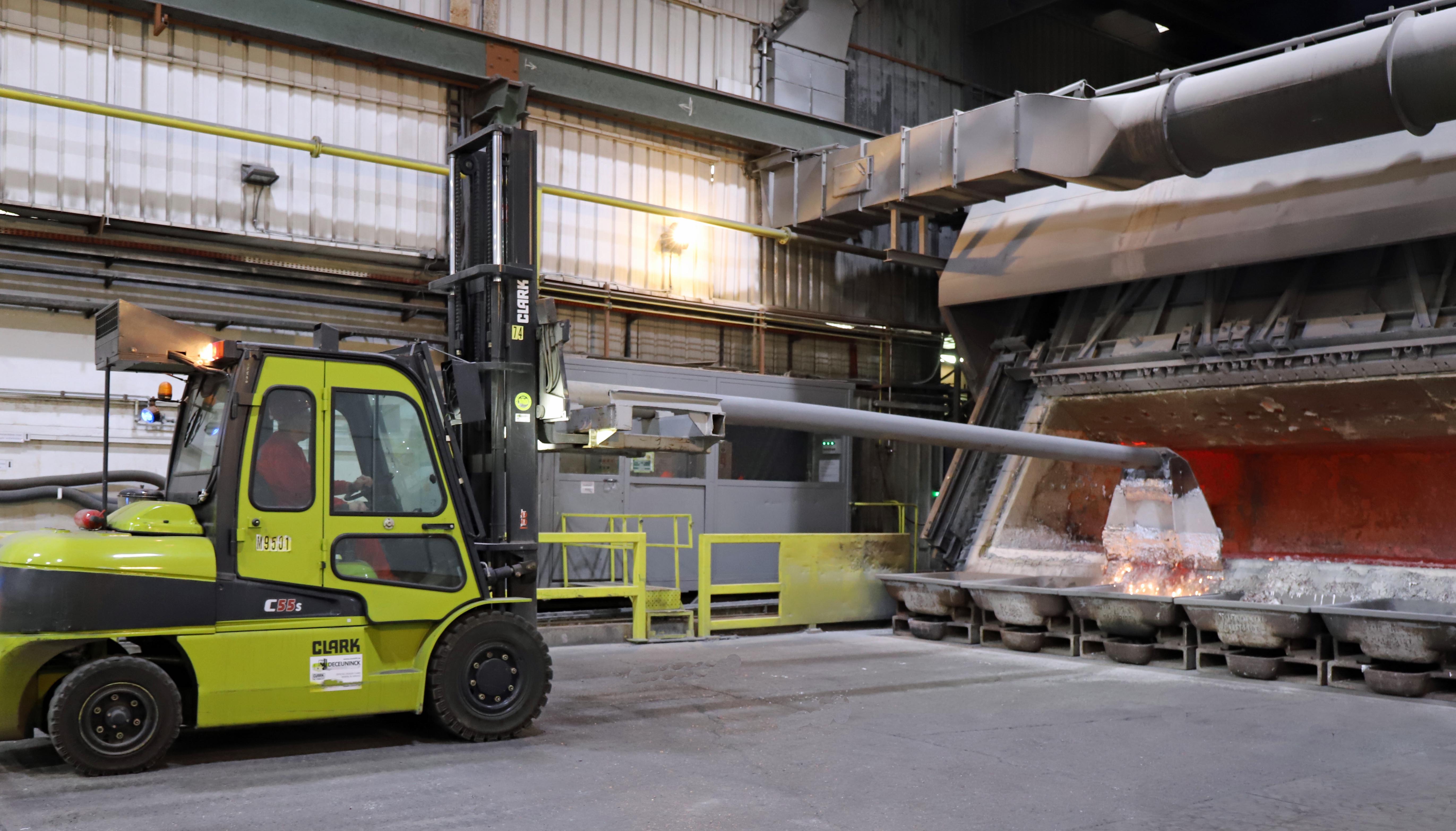 Vorkheftruck aan de smeltoven met lange schraper om overtollige slakken uit de over te verwijderen